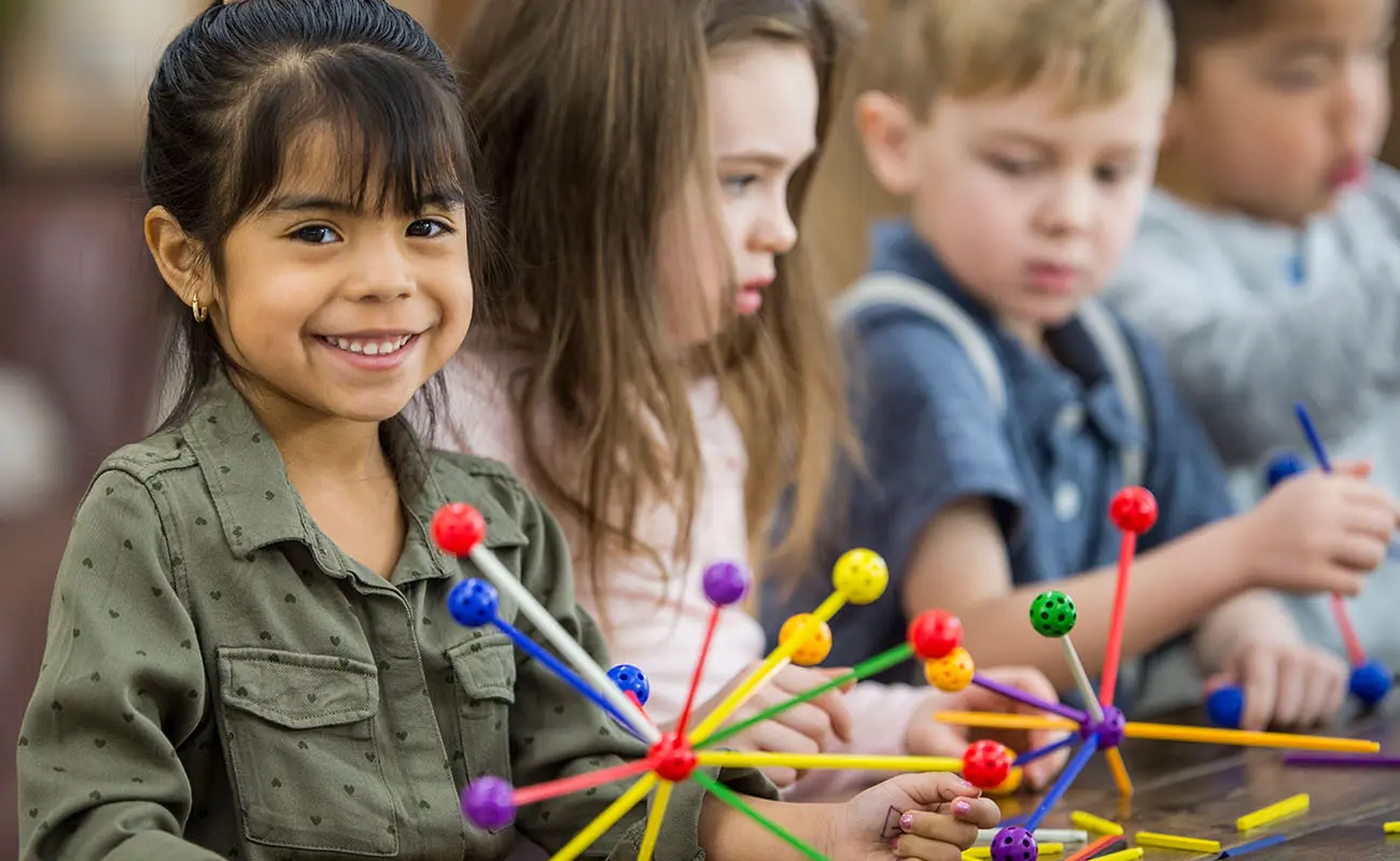 Enfants jouant avec des jouets, une petite fille souriante regardant la caméra