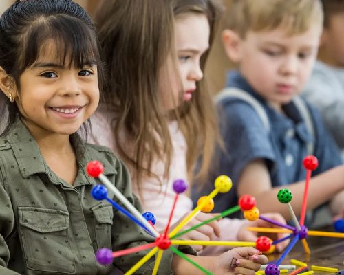 Enfants jouant avec des jouets, une petite fille souriante regardant la caméra