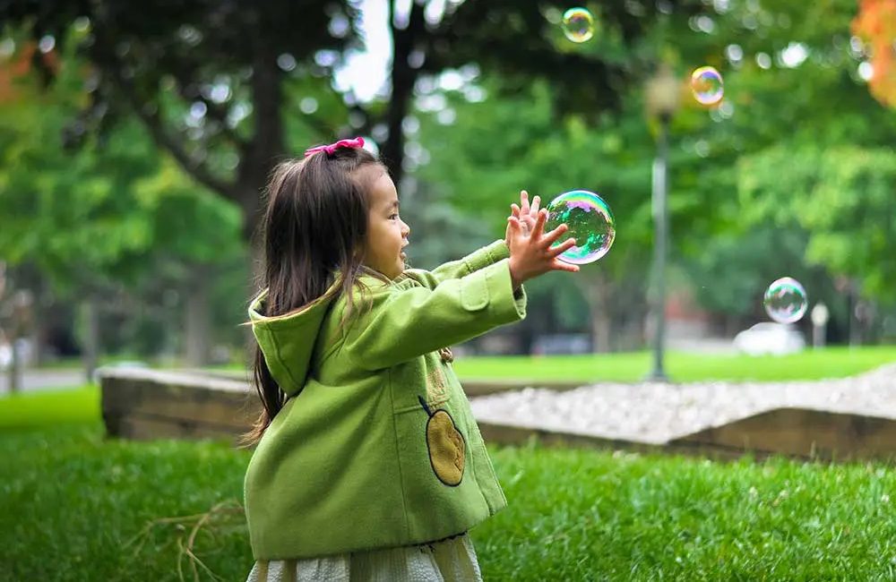 Petite fille jouant avec des bulles d'eau dans le parc