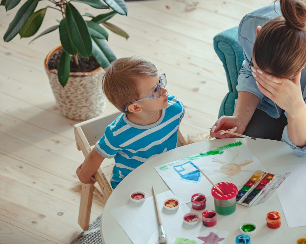 Mère fatiguée et enfant autiste peignent à l'aquarelle ensemble