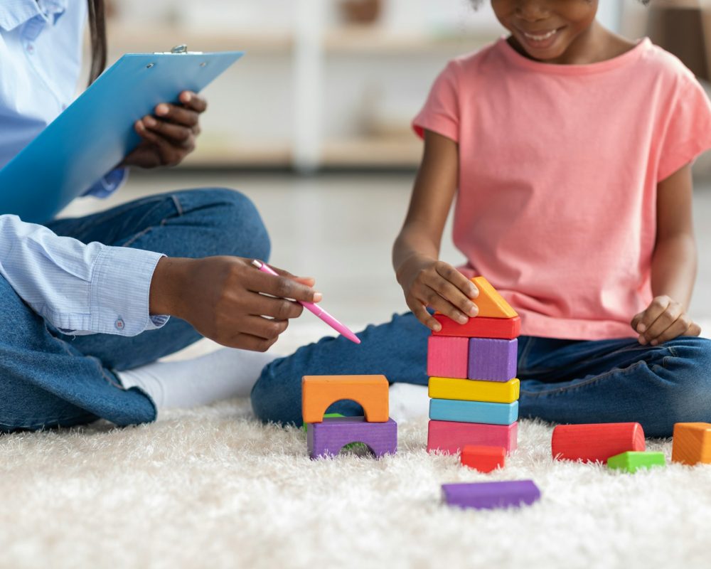 Fille noire et spécialiste du développement de l'enfant faisant une pyramide